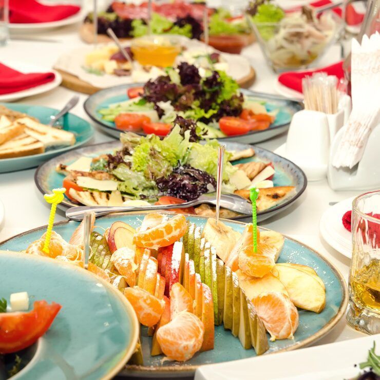 Plates of appetizers and salads on a table at a restaurant, including fruit and greens.