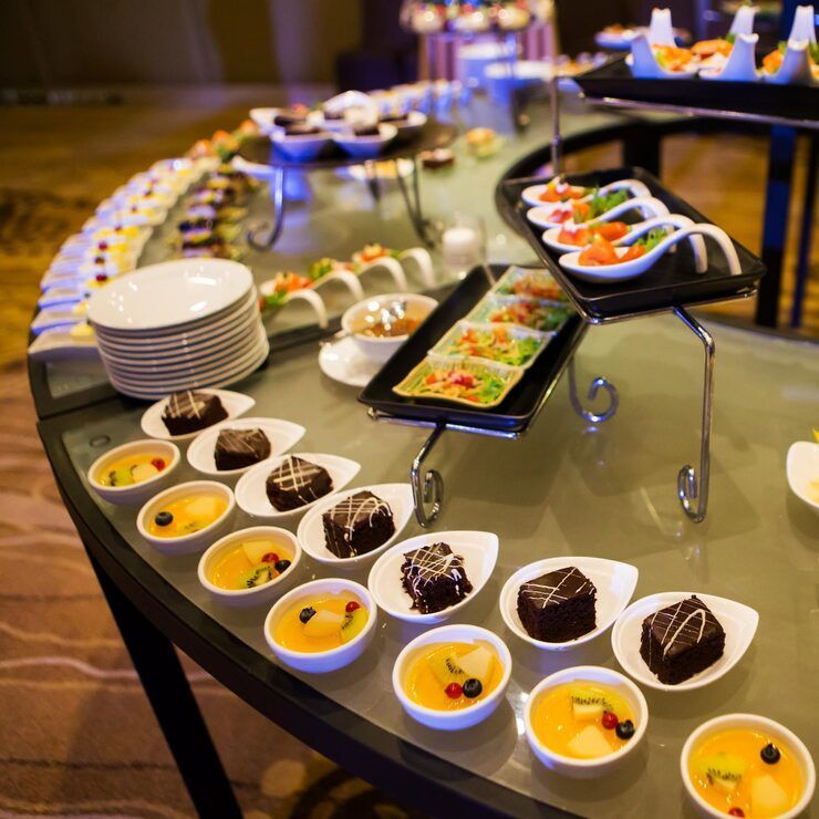 Buffet table with various dishes; servers behind. Elegant dining room setting, food display.