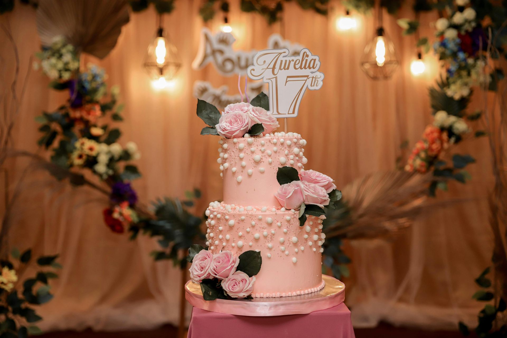 Pink tiered birthday cake with pearl details and floral decor; 