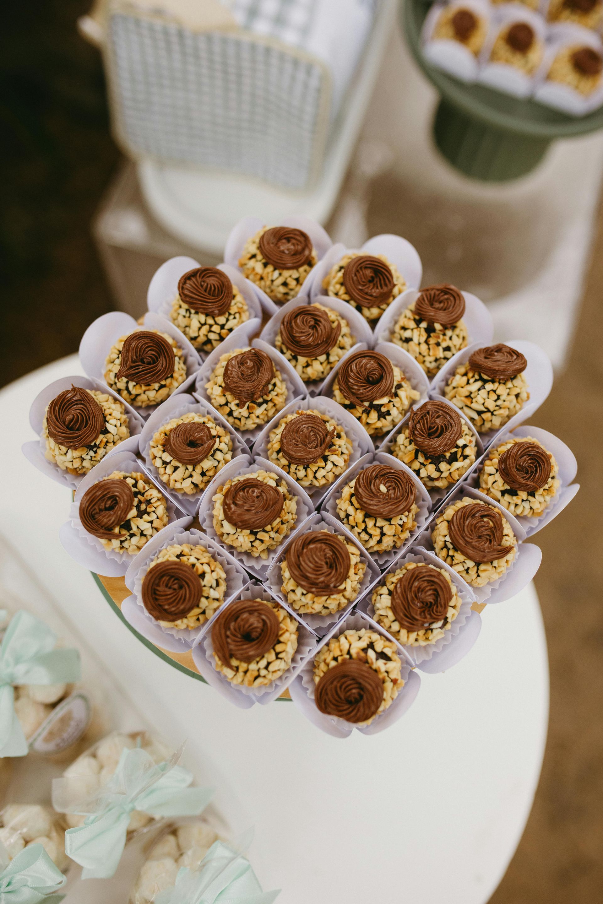 Arrangement of small, round candies with light-colored coating and chocolate topping on a white surface.