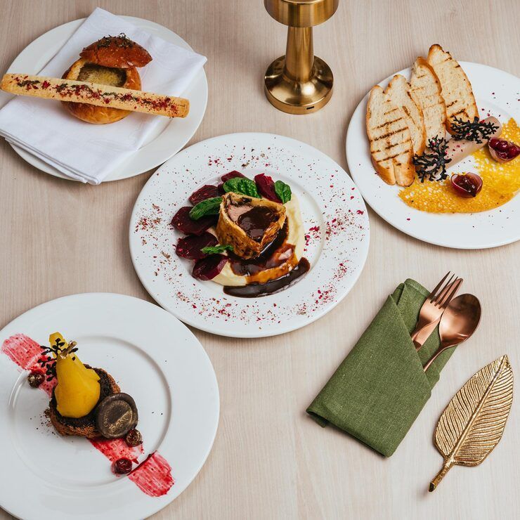Overhead view of a table set with multiple plates of gourmet food and cutlery.
