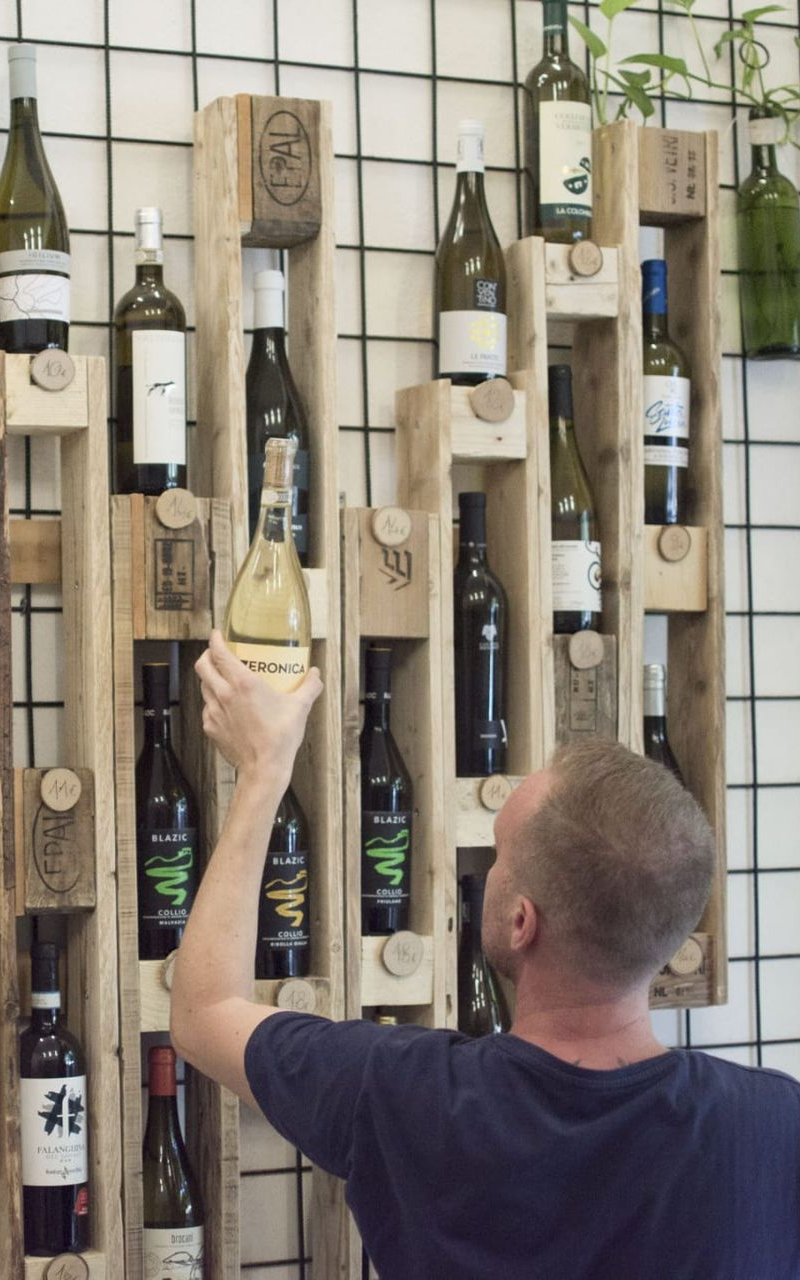 Il titolare di Sfusi Milano davanti ad alcune bottiglie di vino