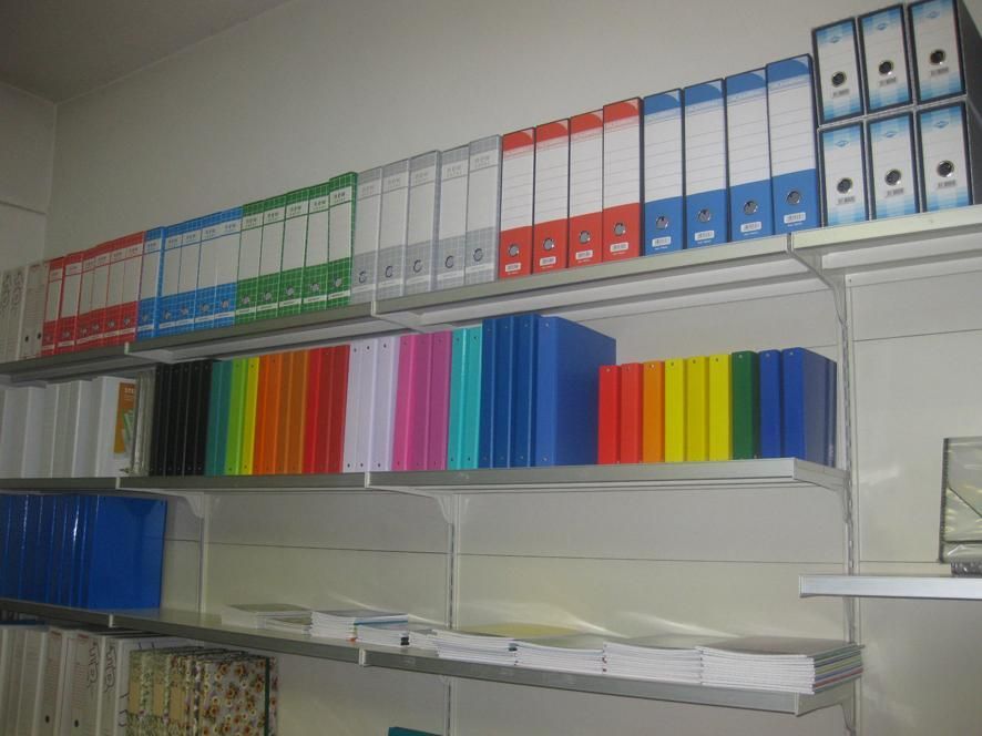 Scaffali pieni di raccoglitori colorati: rosso, blu, verde e bianco. Situato in un ambiente d'ufficio.