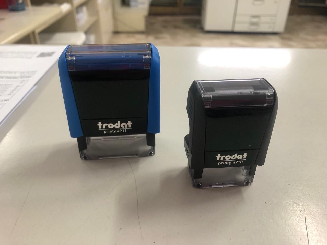 Due timbri Trodat blu e neri su una superficie bianca. Uno è più grande dell'altro.
