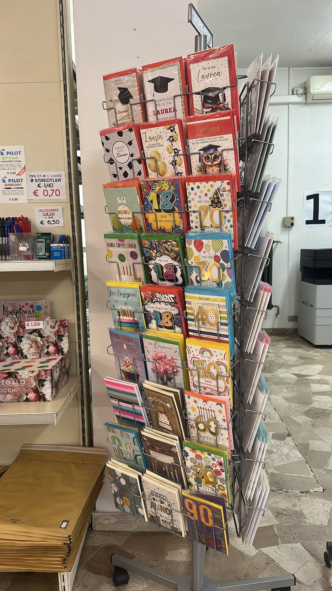 Biglietti d'auguri esposti su uno scaffale girevole all'interno di un negozio.
