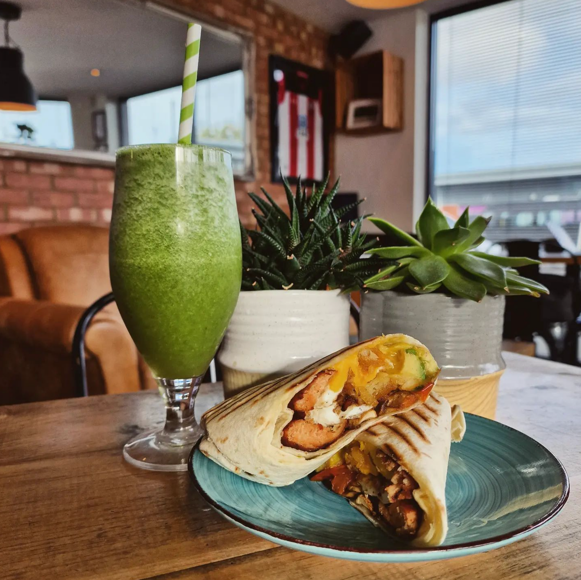 a sandwich and a green smoothie are on a plate on a table .
