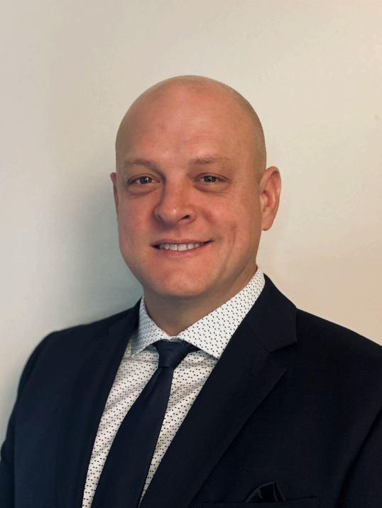 A man in a suit and tie is smiling for the camera