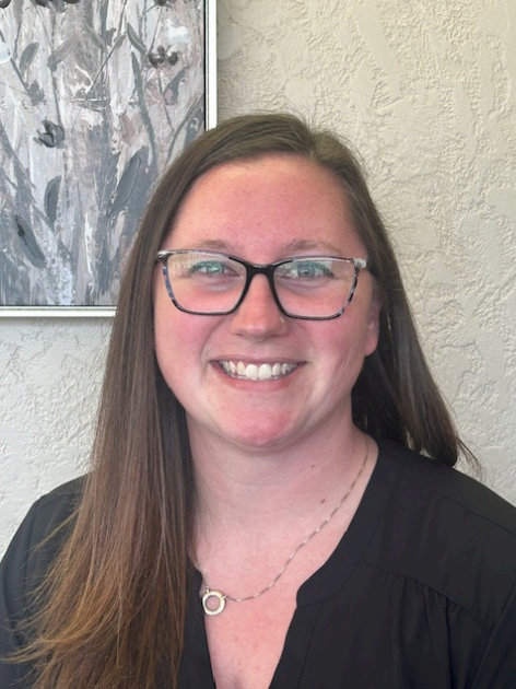 A woman wearing glasses and a black shirt is smiling for the camera.