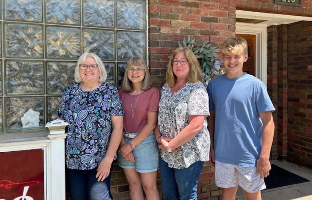 A group of people are standing in front of a brick building.