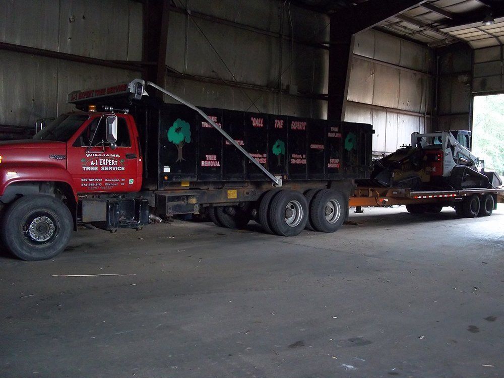 A red dump truck with a tractor behind — Dowagiac, MI — Williams A-1 Expert Tree Service