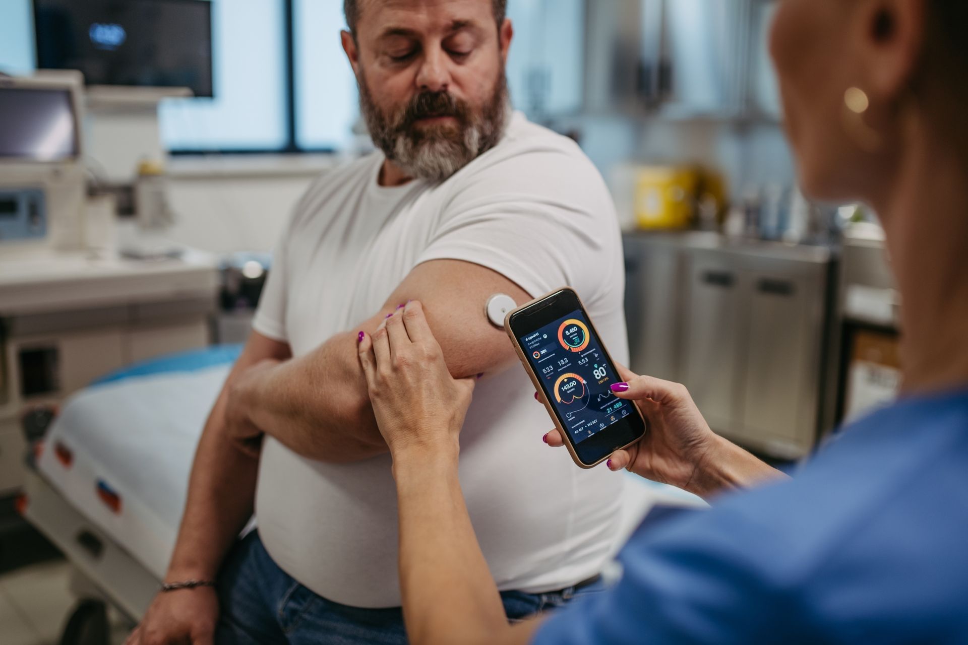 A nurse is putting a device on a man 's arm electronically reviewing his glucose levels.