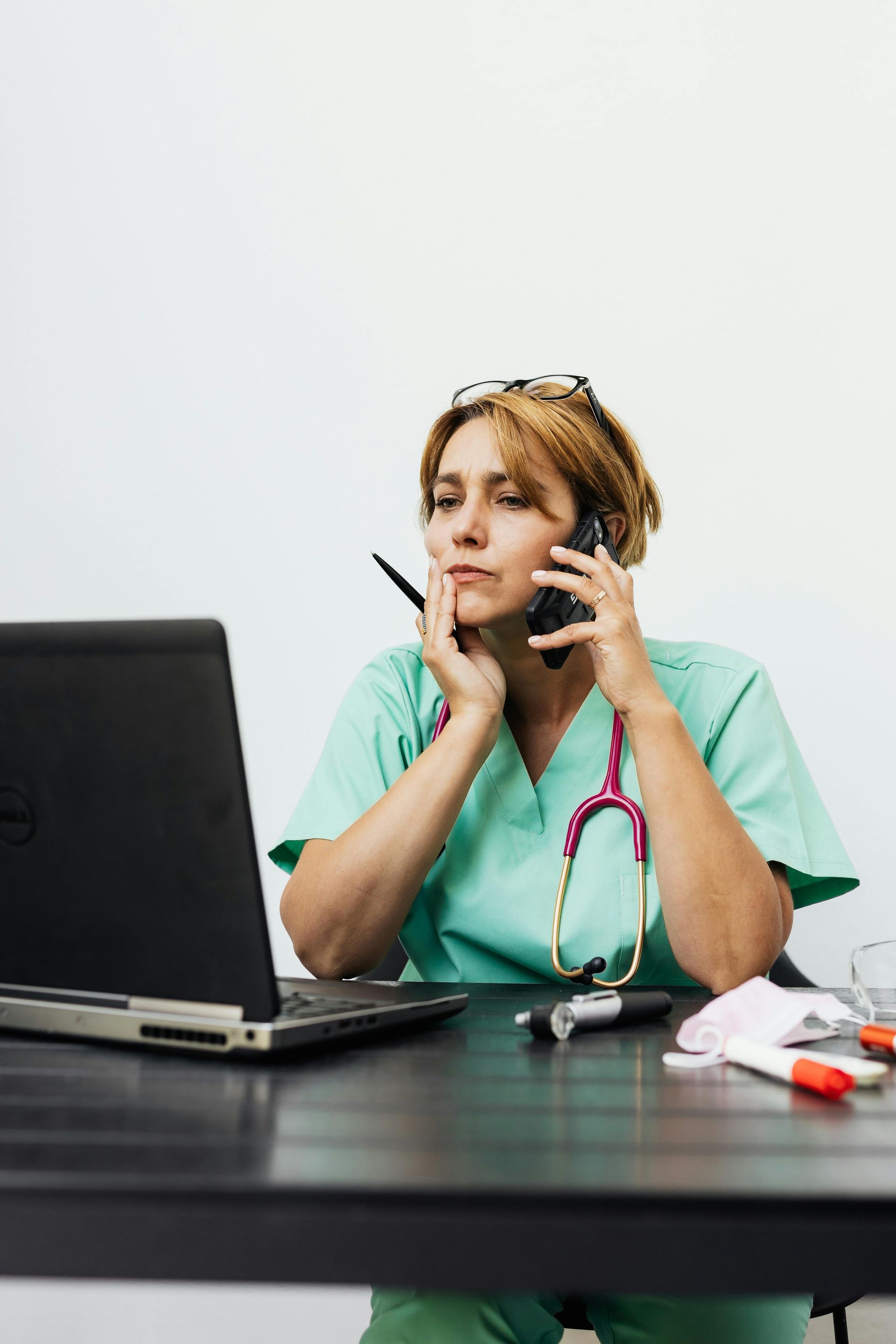 Medical assistant is sitting in front of a computer while speaking with a patient on the phone