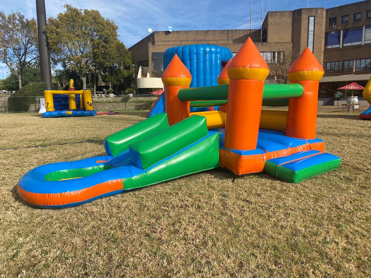 A bouncy castle with a slide and a water slide in a park.
