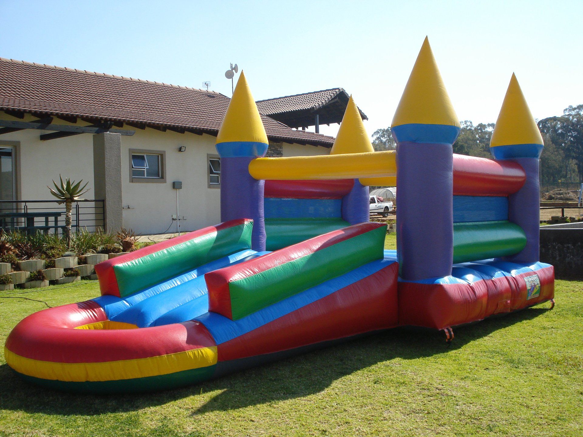 A colorful bouncy castle is sitting in the grass in front of a house