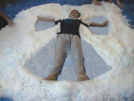 A child is laying in a pile of snow in the shape of a peace sign