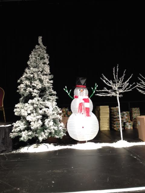 A snowman is standing in front of a christmas tree