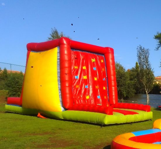A red and yellow bouncy house with a climbing wall