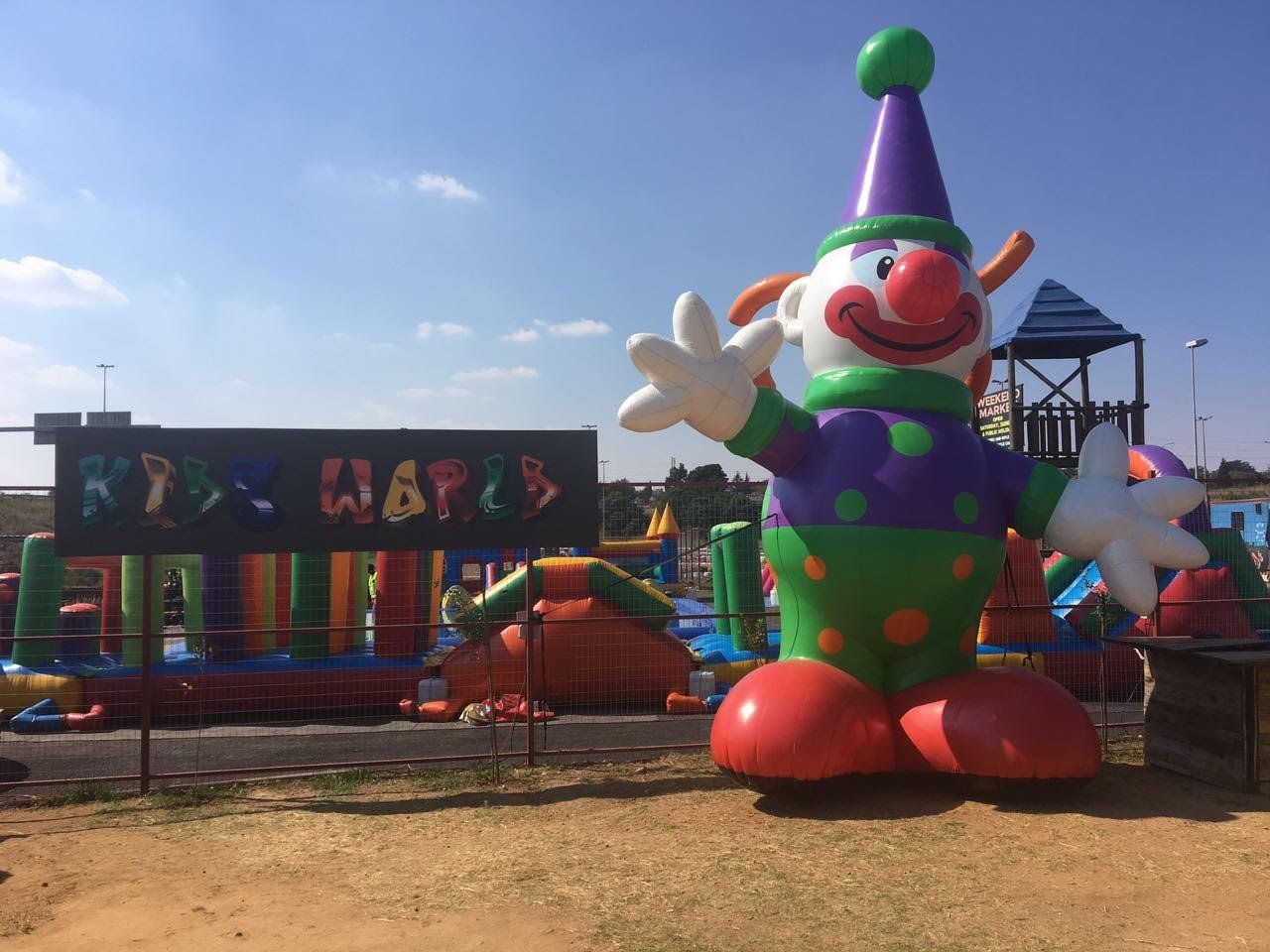 A large inflatable clown is standing in front of a bouncy house.
