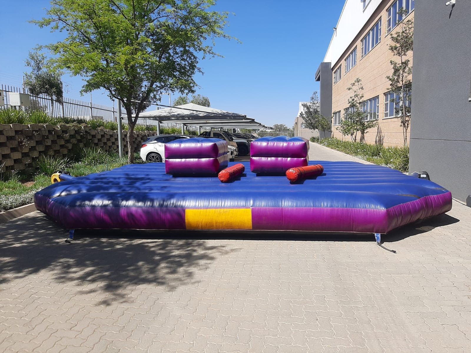 A purple inflatable couch is sitting on a brick sidewalk in front of a building.