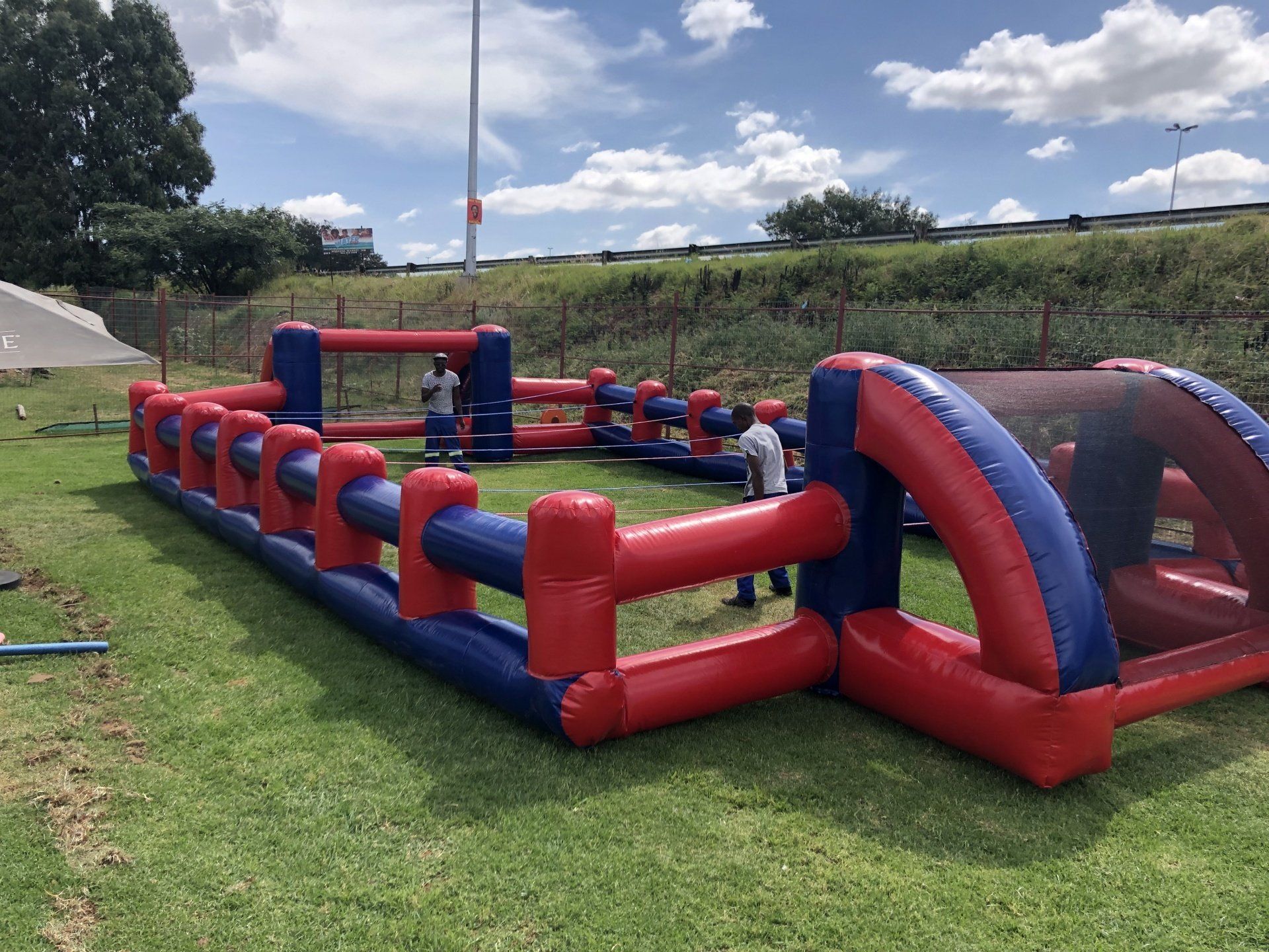 A red and blue inflatable fence is sitting on top of a lush green field.