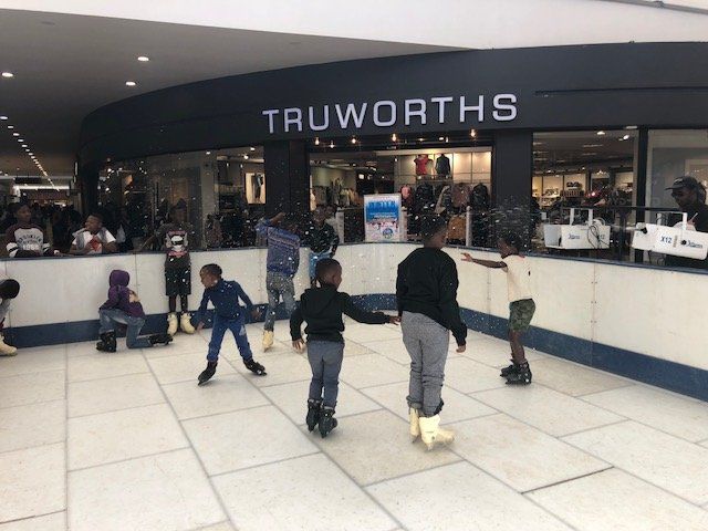 People are ice skating in front of a truworths store