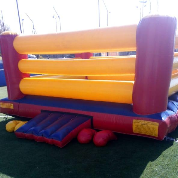 A red and yellow bouncy ring with boxing gloves on the ground