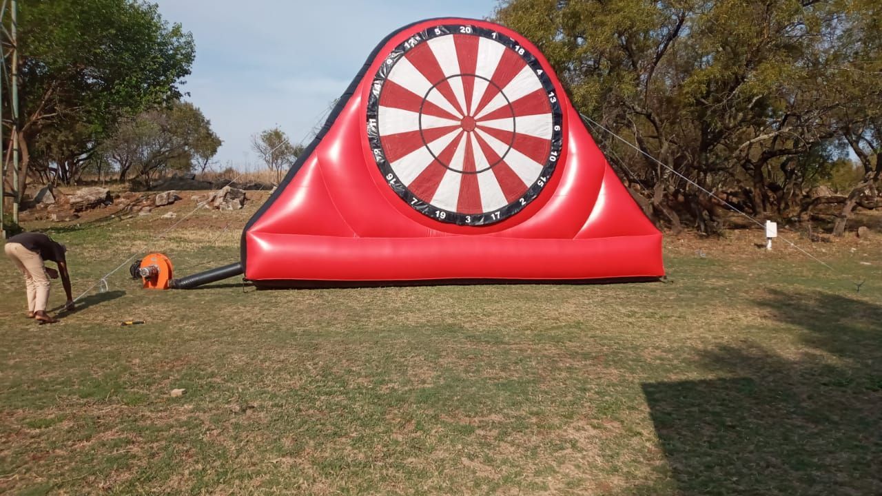 A large inflatable dart board is sitting in a grassy field.