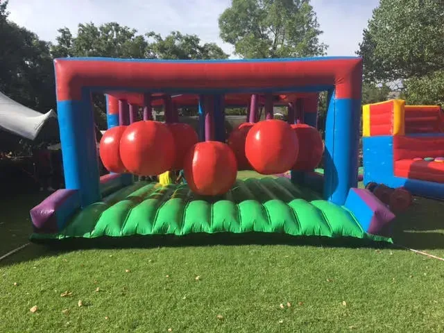 A large inflatable obstacle course is sitting on top of a lush green field.