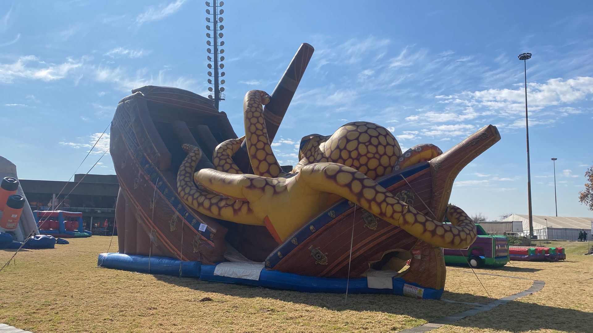A large inflatable octopus is laying on top of a pirate ship.
