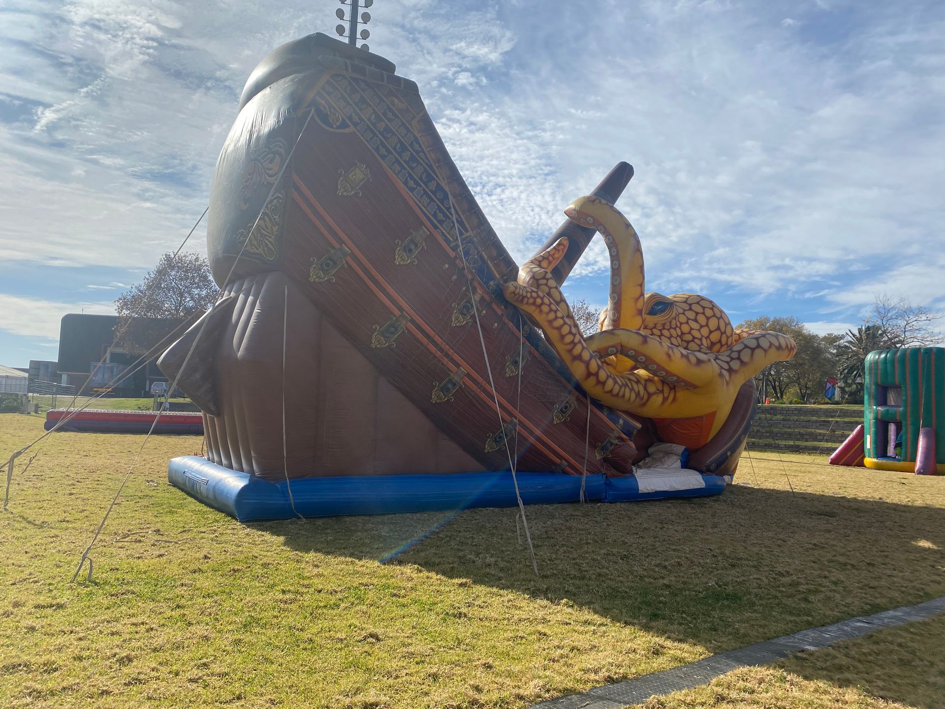 A large inflatable pirate ship is sitting on top of a lush green field.