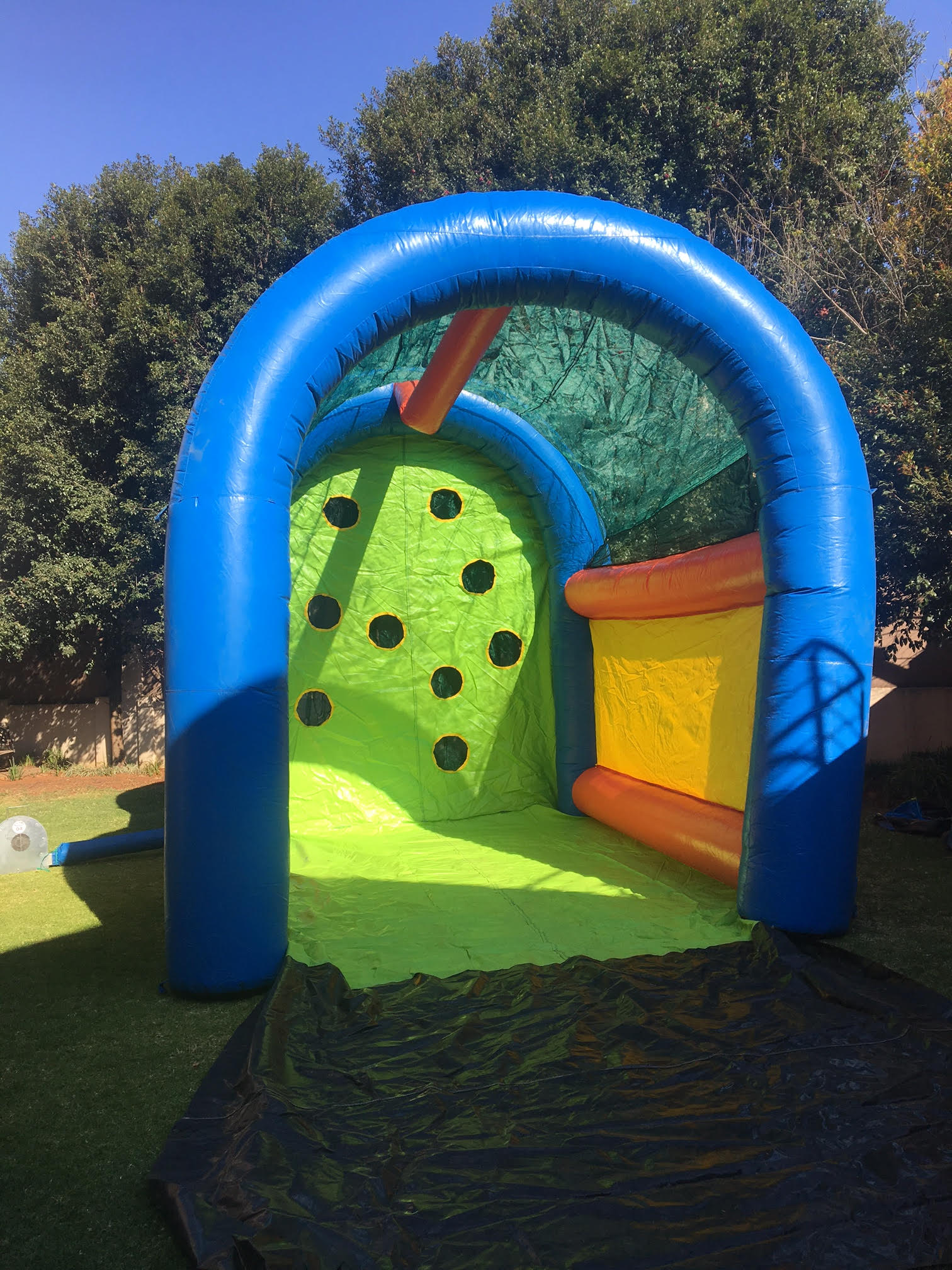 A large inflatable bouncy house is sitting on the ground in a backyard.