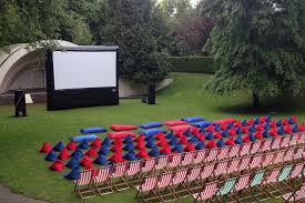 A row of chairs in front of a large inflatable screen in a park.