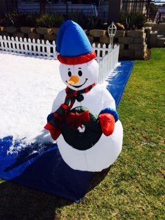 An inflatable snowman with a blue hat and scarf is standing in the snow.