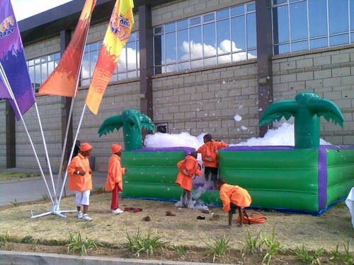 A group of children are playing on a bouncy house with foam coming out of it.