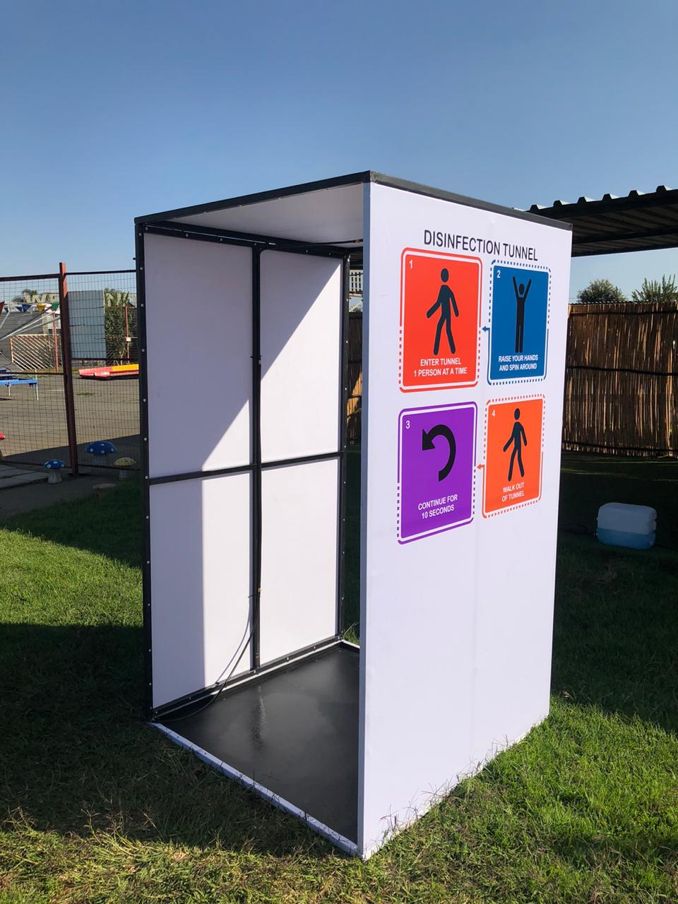 A white box with signs on it is sitting on top of a lush green field.