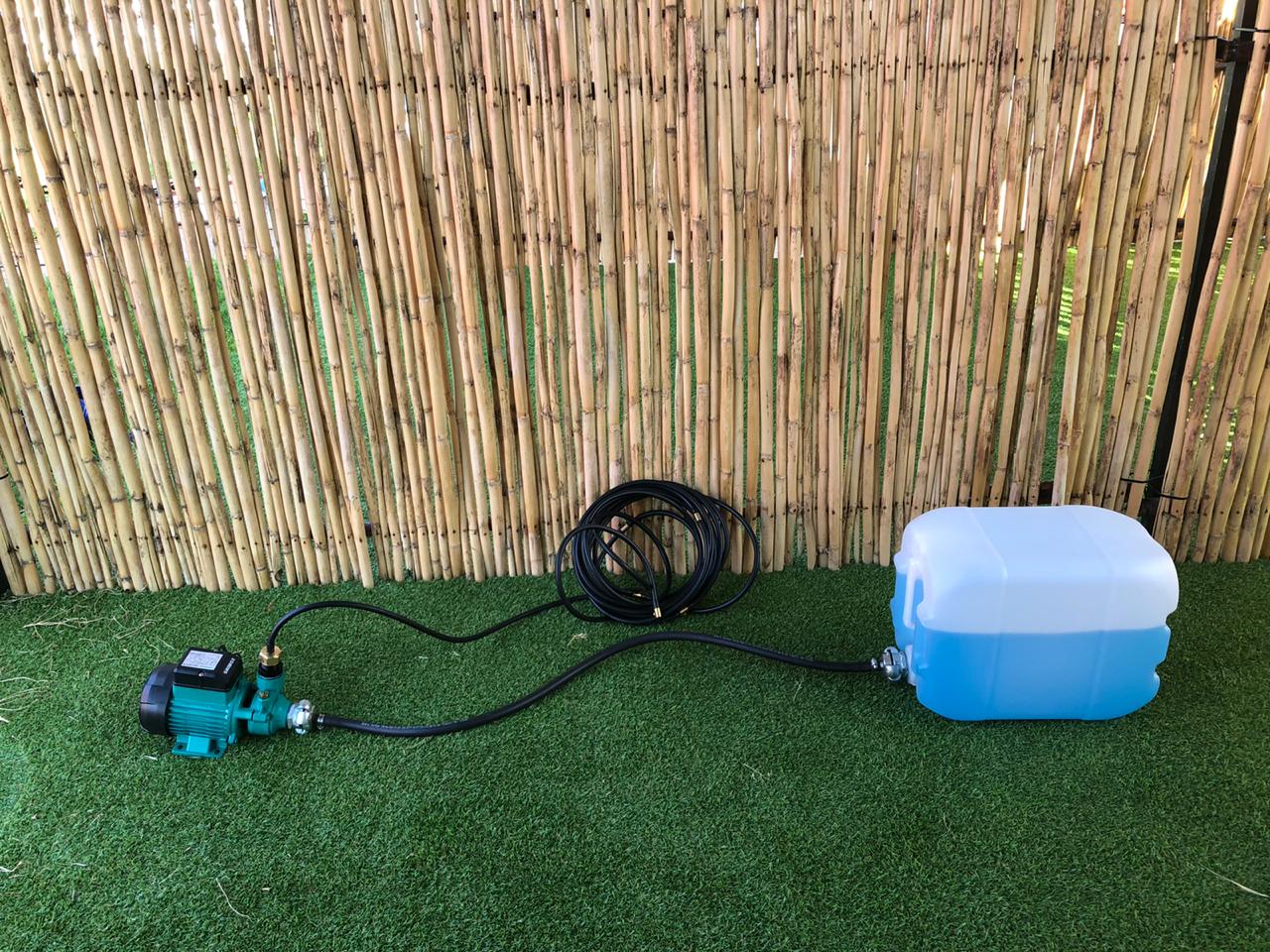 A water pump is attached to a blue bucket on a lush green lawn.