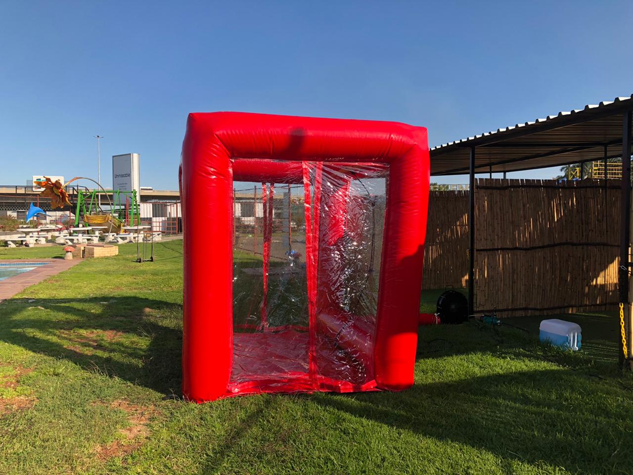 A red inflatable cube is sitting on top of a lush green field.