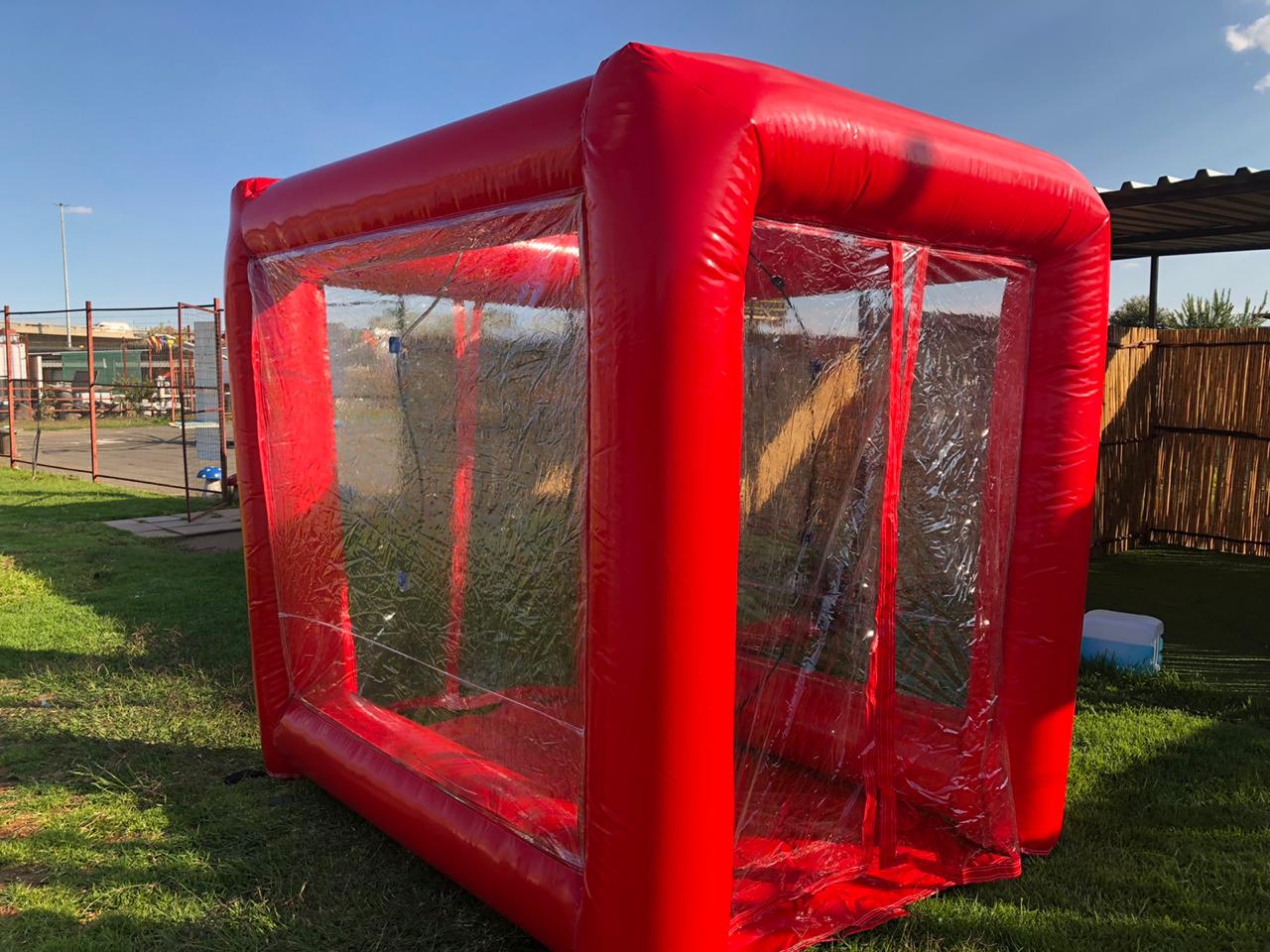 A red inflatable soccer goal is sitting on top of a lush green field.