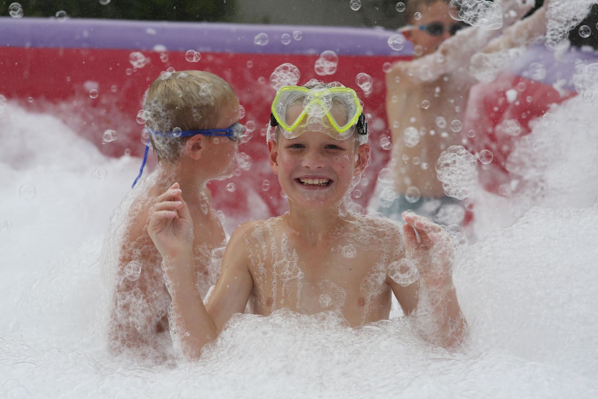 Two young boys are playing in a pool of foam.