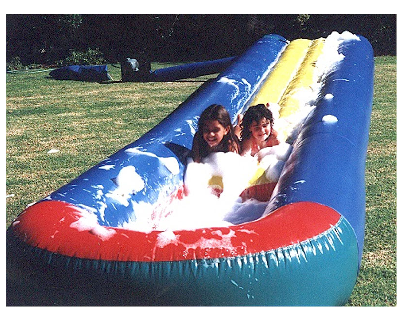 Two girls are riding down a foamy inflatable slide
