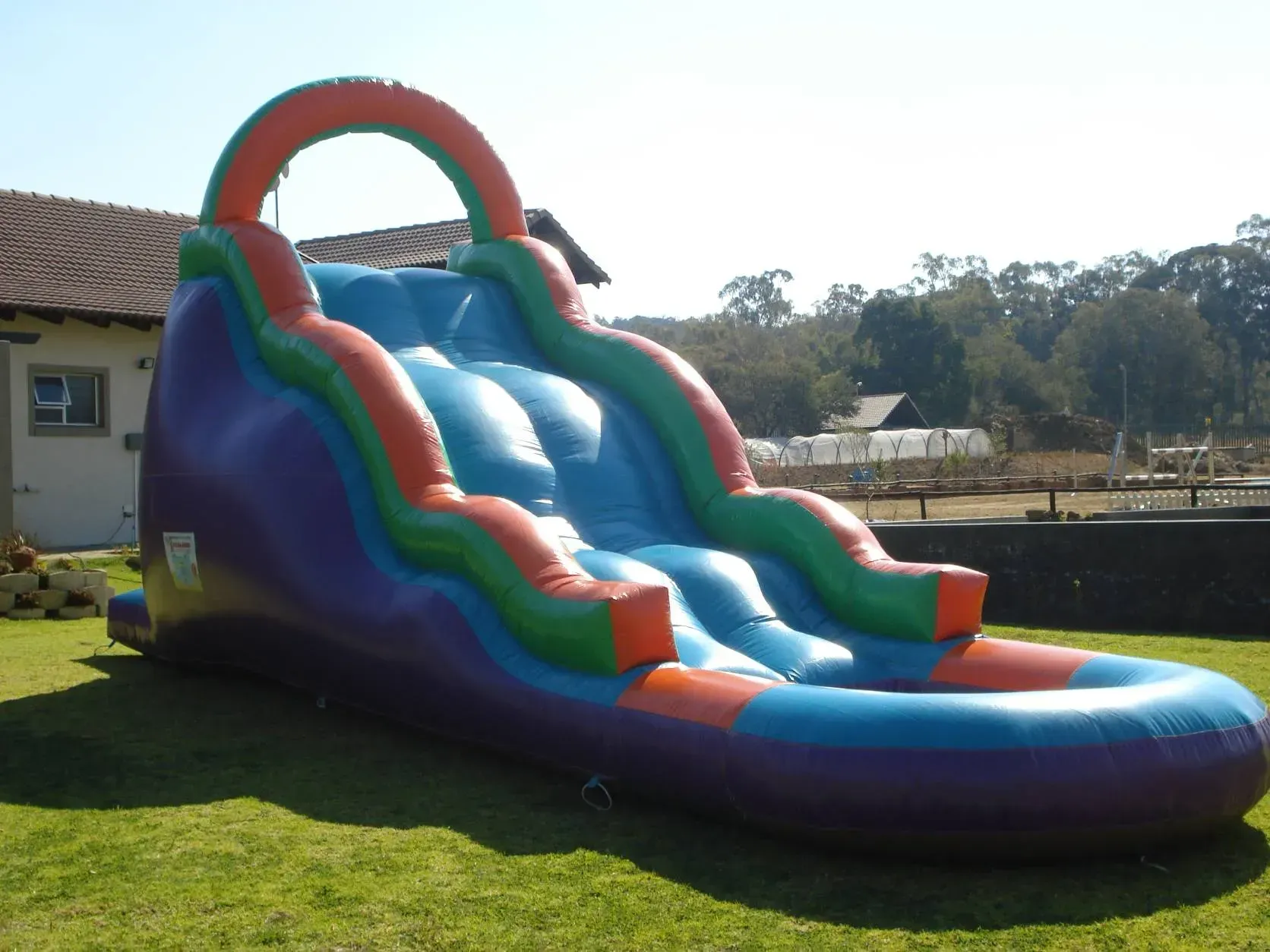 A large inflatable water slide is sitting in the grass in front of a house