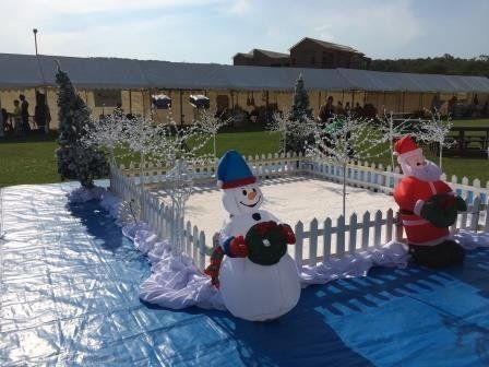 A snowman and santa claus are sitting in a fenced in area