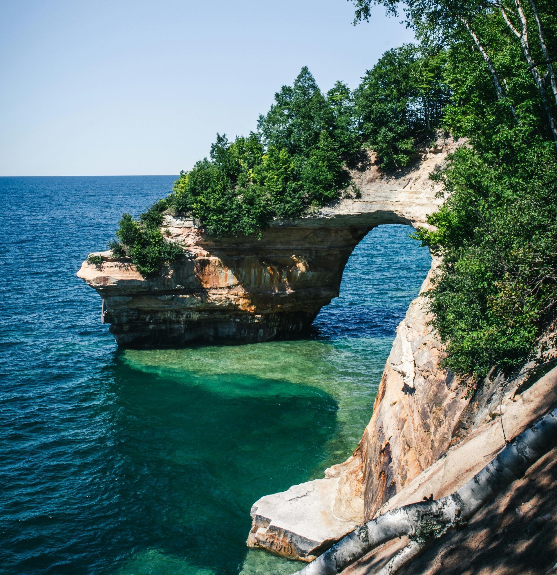 A crescent moon is rising over a mountain covered in fog.