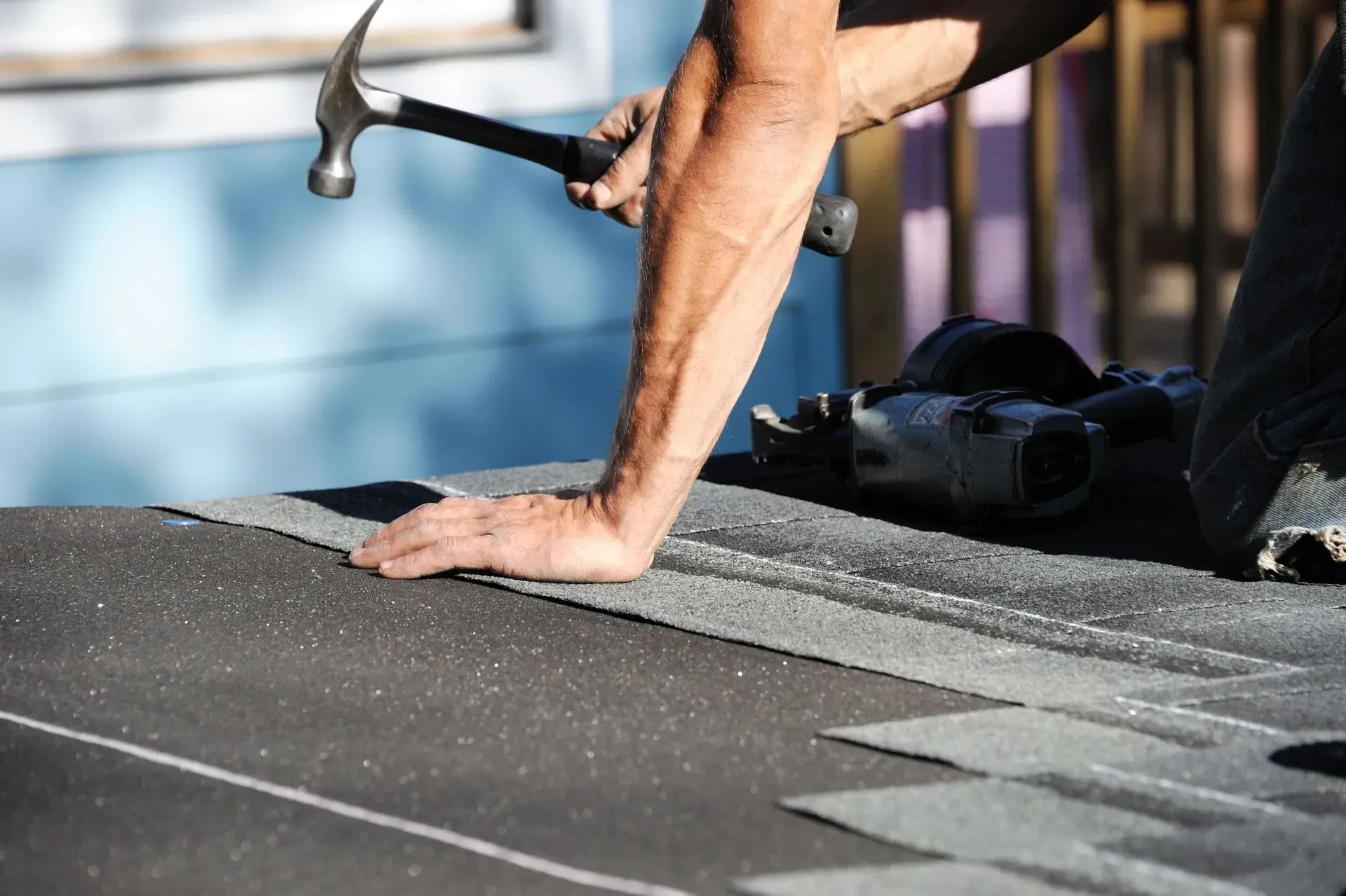 A man is measuring the roof of a house with a tape measure.