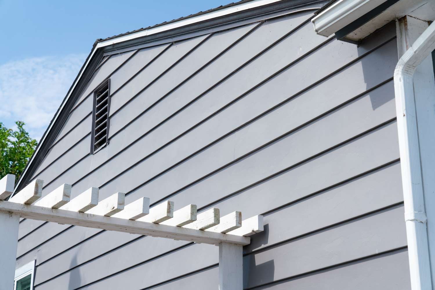 A man is measuring the roof of a house with a tape measure.