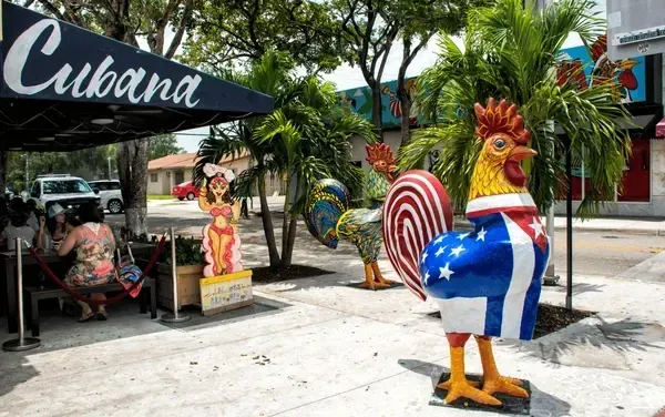 A statue of a rooster in front of a restaurant called cubana