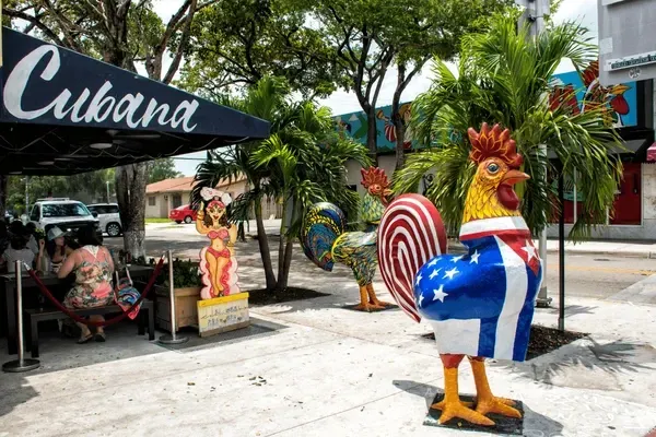 A statue of a rooster in front of a restaurant called cubana