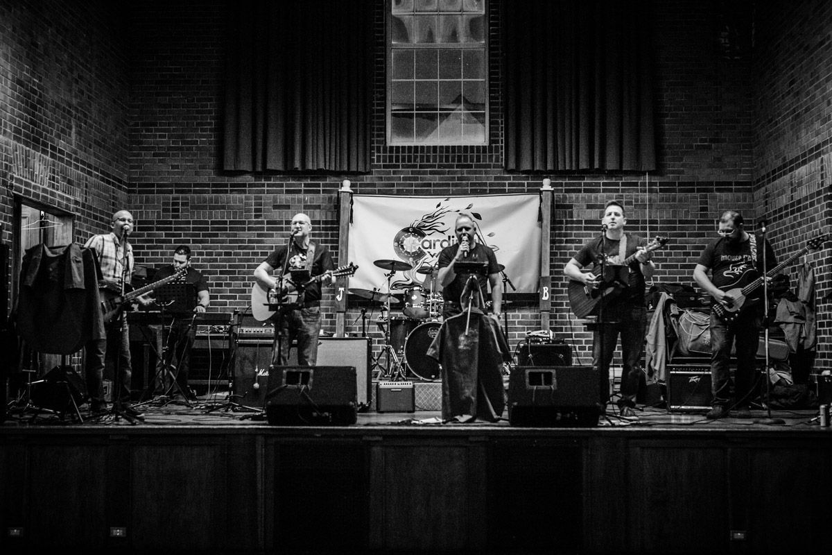 A black and white photo of a band playing instruments on a stage.