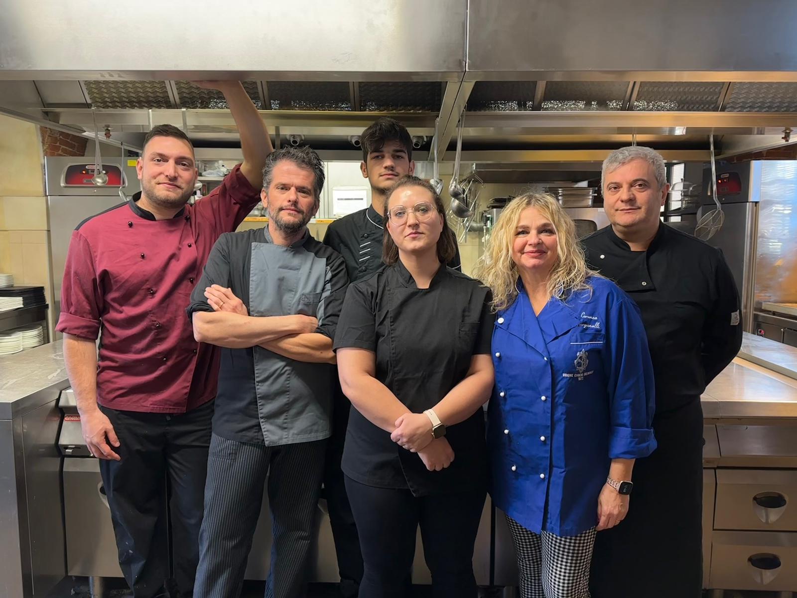 Un gruppo di chef in piedi nella cucina di un ristorante.