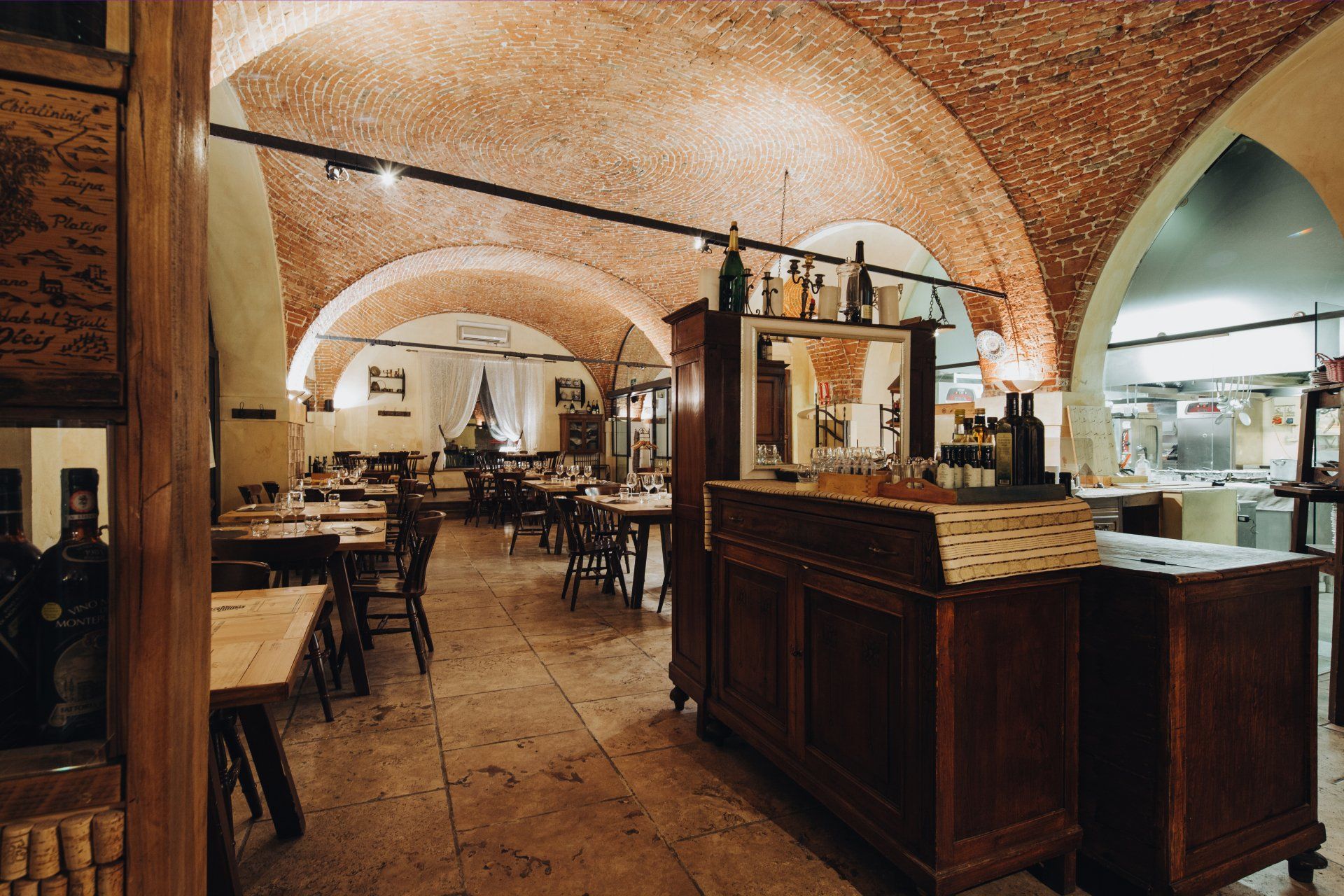 Interno del ristorante con archi in mattoni e tavoli in legno, con zona bar.